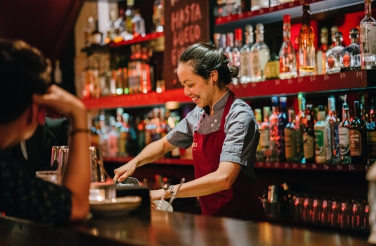woman bartender smiling while mixing liqueurs 1301547 v2